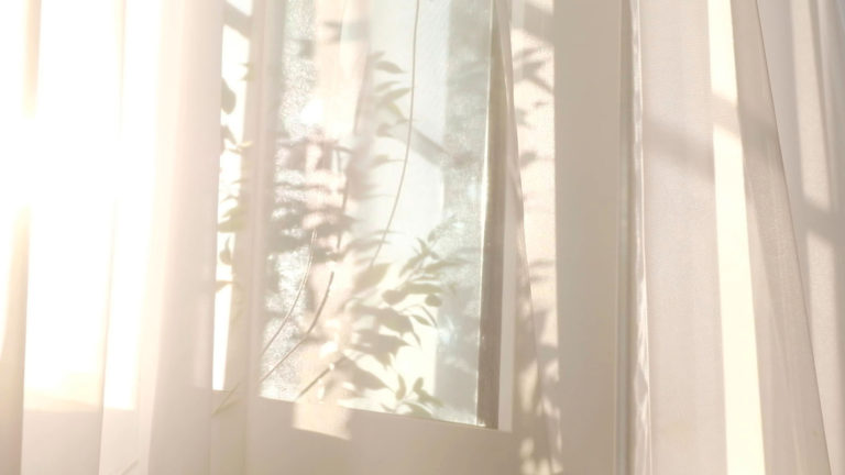 Shadows of tree branches show through a gauzy curtain over a window showing the importance of having sharp ears and soft hearts to hear God's voice.