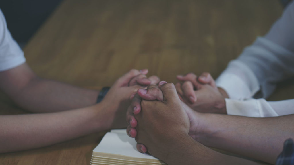 Three sets of hands clasped in prayer show how to strengthen bonds by praying for one another.