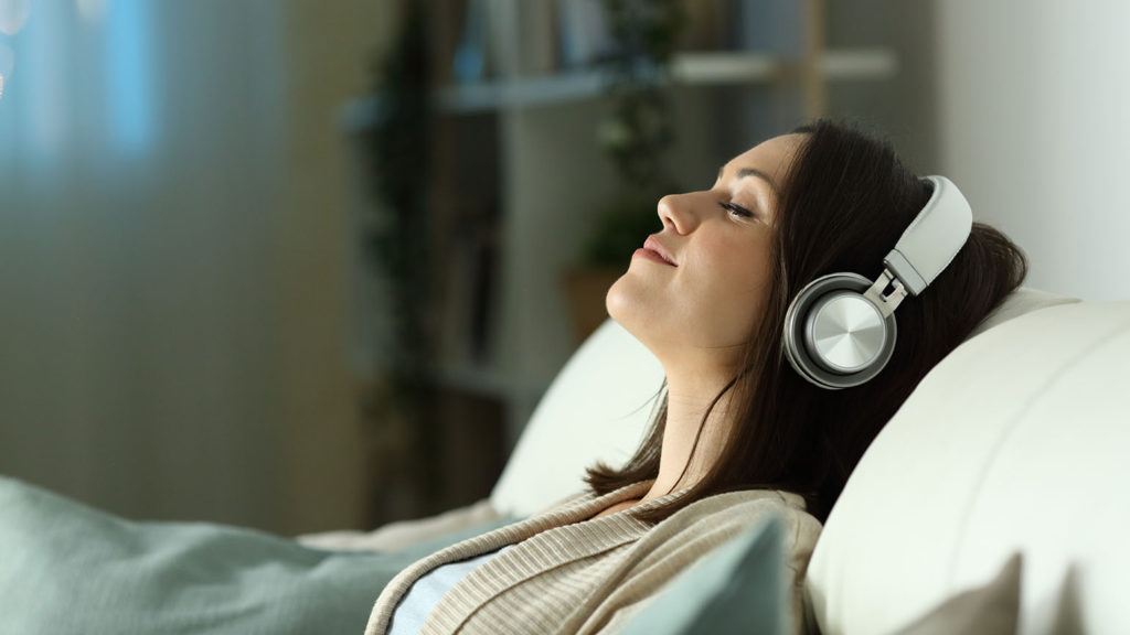 A young woman listens on headphones to a Christian evening meditation.