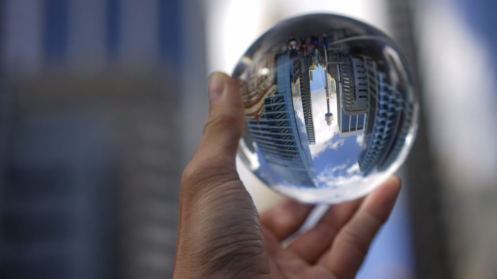 A reflection ball held in a hand showing an upside down city reminds us that God's goodness can sometimes be missed.