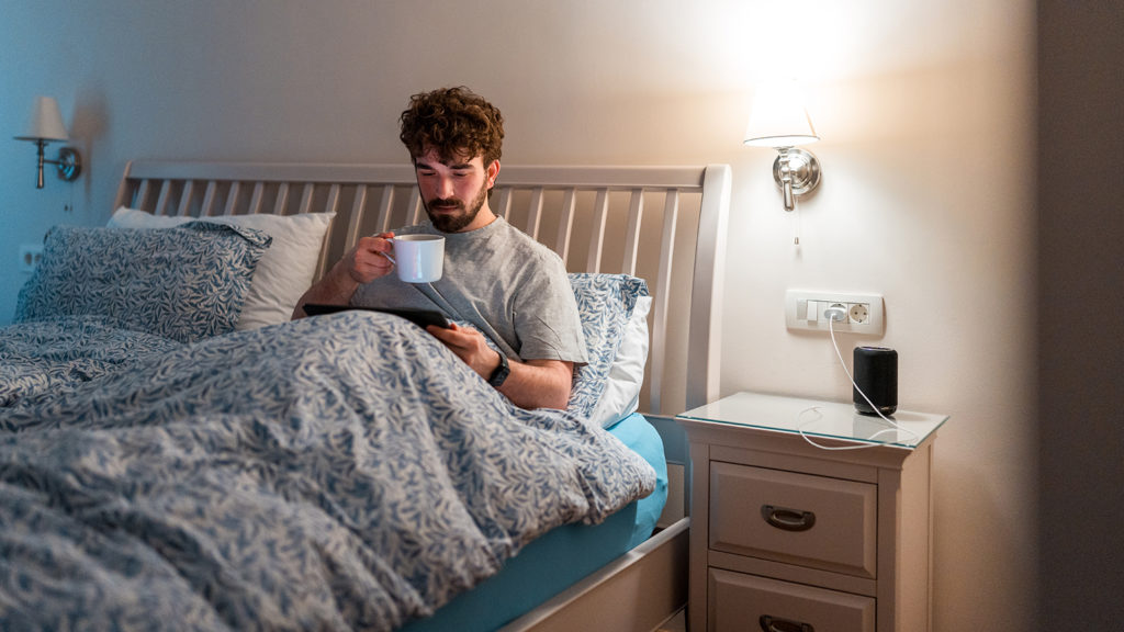 Man reading a book before bed as a part of his nighttime routine for better sleep