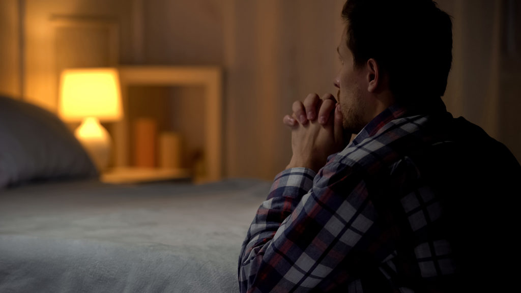 Man saying a bedtime prayer for his wife