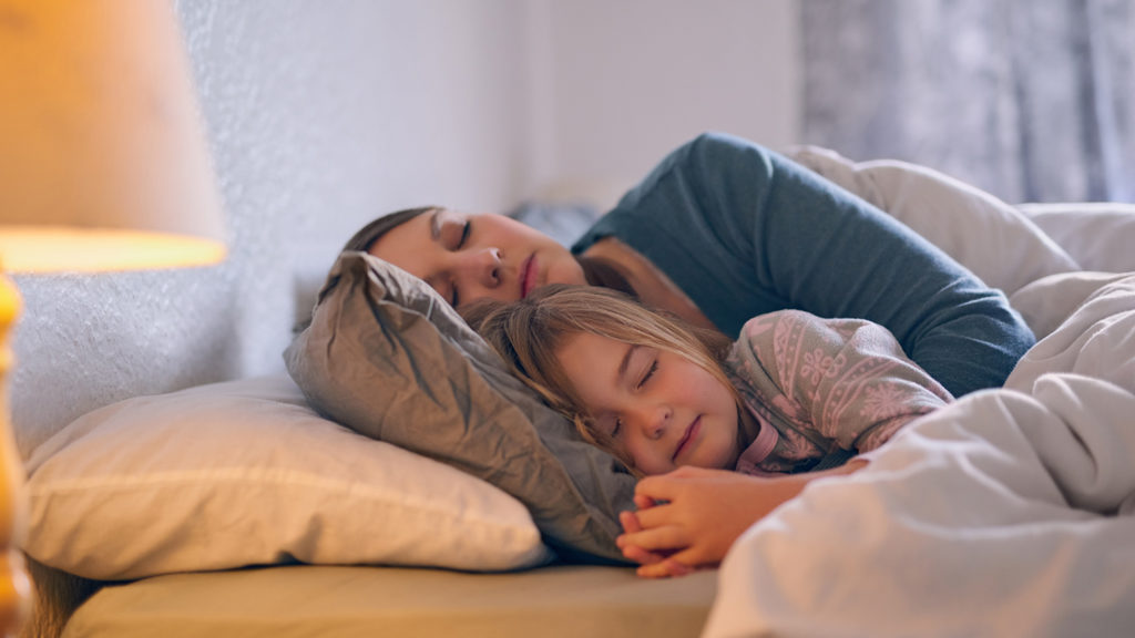 Mother and child sleep in bed as part of their sleep tips