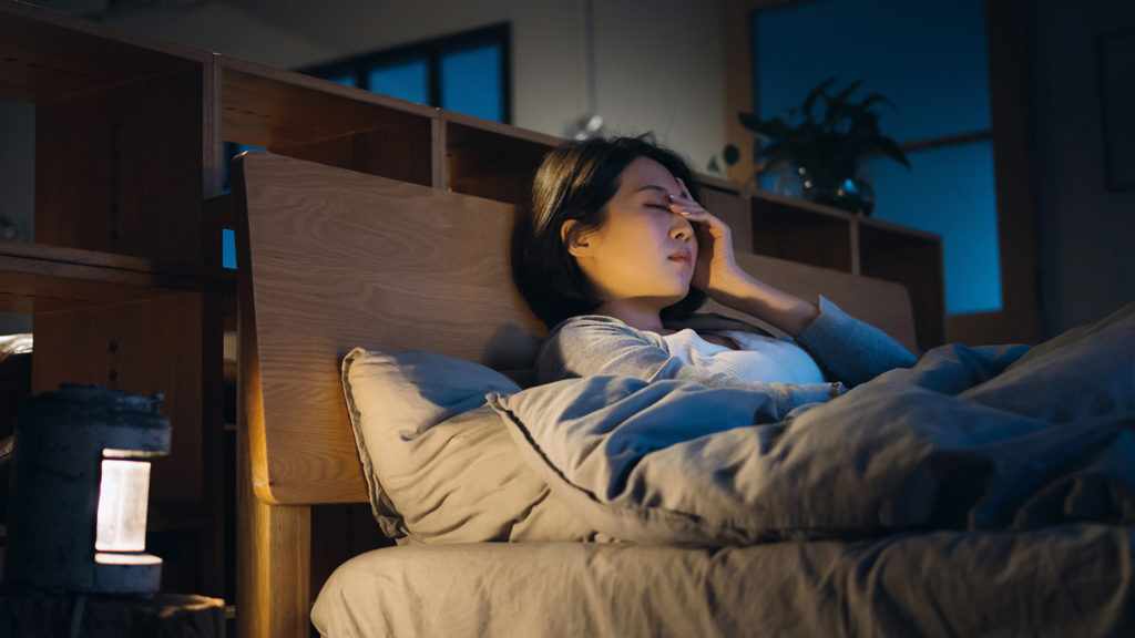 Woman sitting in bed unable to sleep better because of insomnia