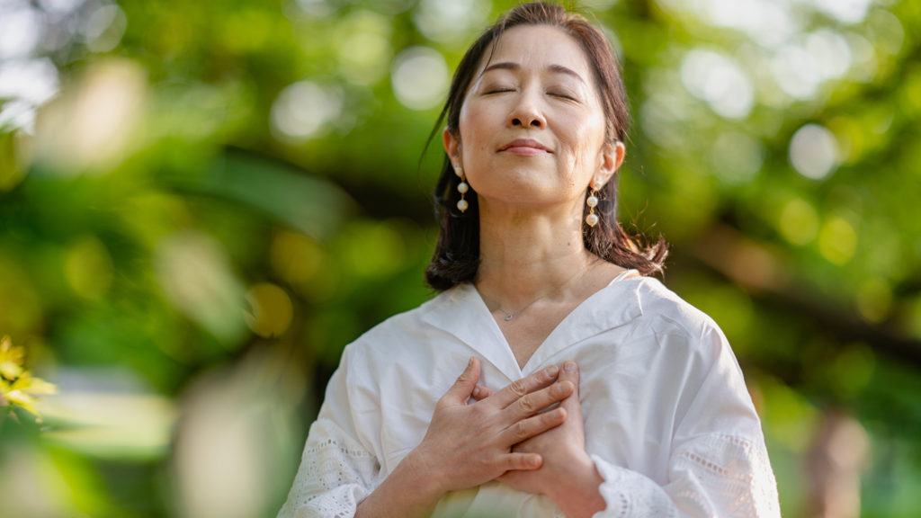 Royalty-Free Stock Photo: Woman in nature with her hands over her heart.