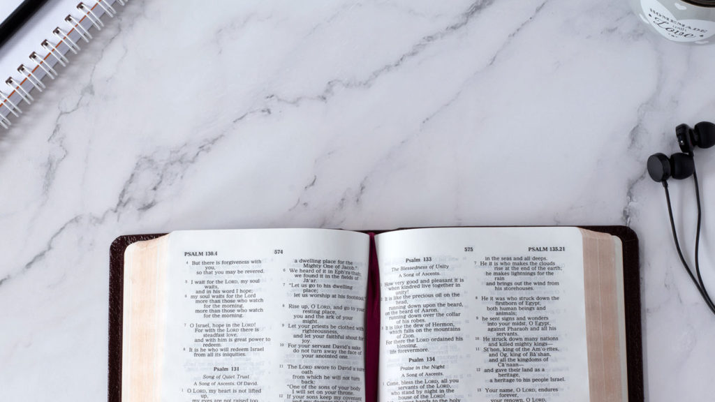 An open Bible on a white marble desk shows that listening to God means spending time in His Word.