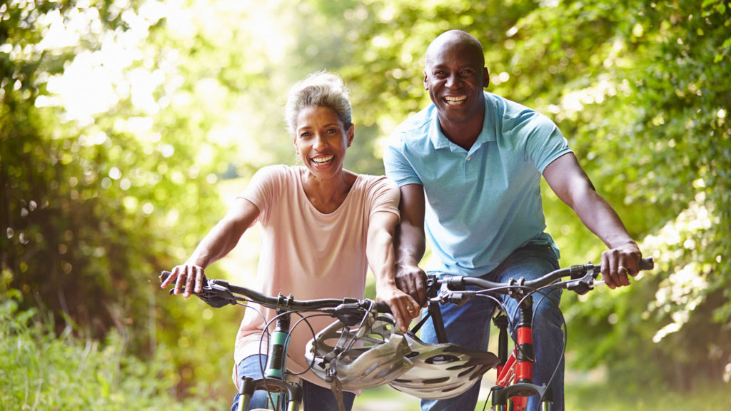 An older African-American couple rides bikes for exercise to help with sleep and aging.