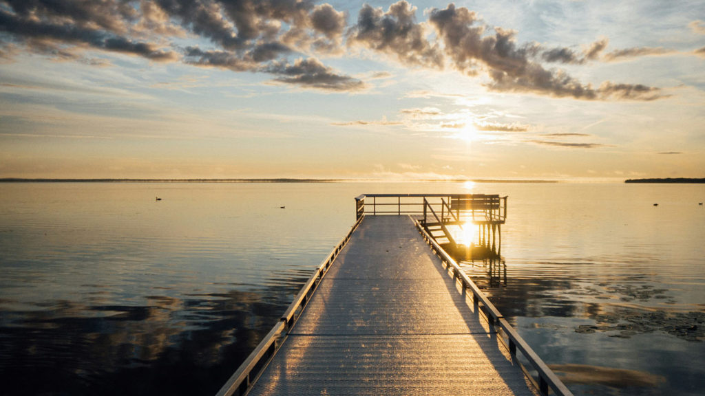 A dock reaches out into the ocean at sunrise delighting you as you have found a sleep deprivation solution.