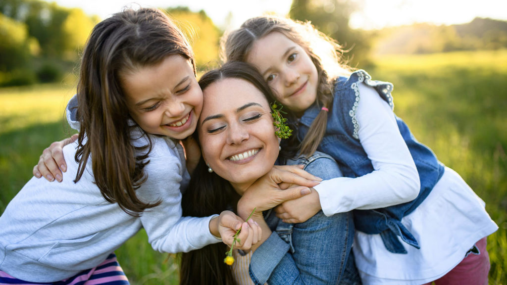 A mom smiles with her two small girls as she is no longer a sleep-deprived mom.