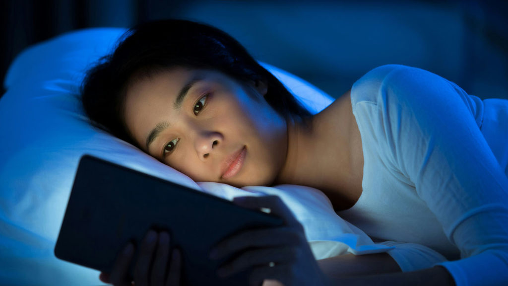 Young Asian woman find rest at night with a peaceful sleep meditation on her tablet.