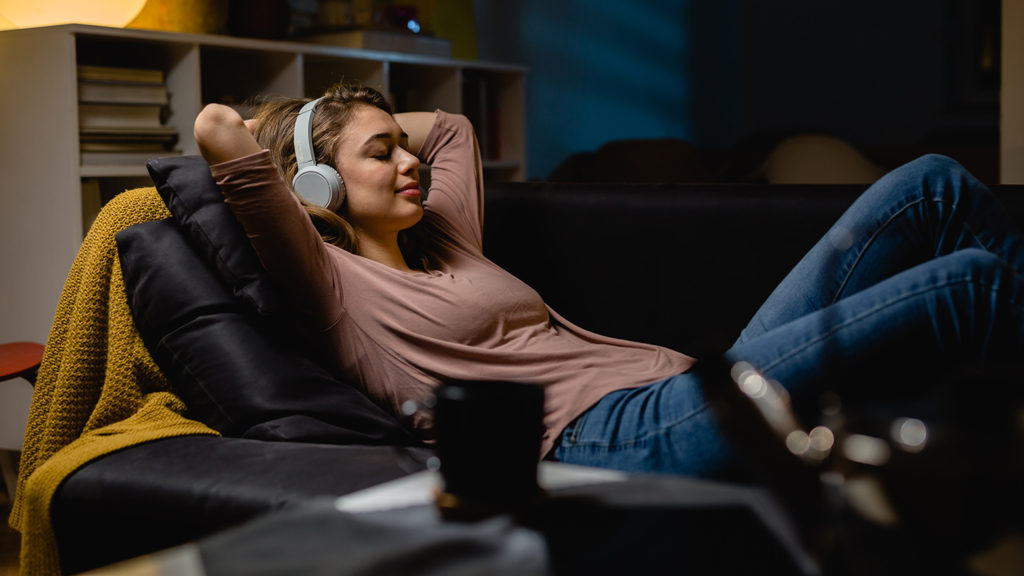 Royalty-Free Stock Photo: Young woman relaxing at home and listening to a sleep meditation on her headphones.