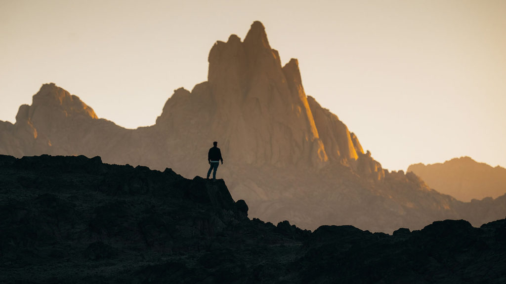 A man stands in silhouette before a mountain peek at sunset knowing he is understood by God.