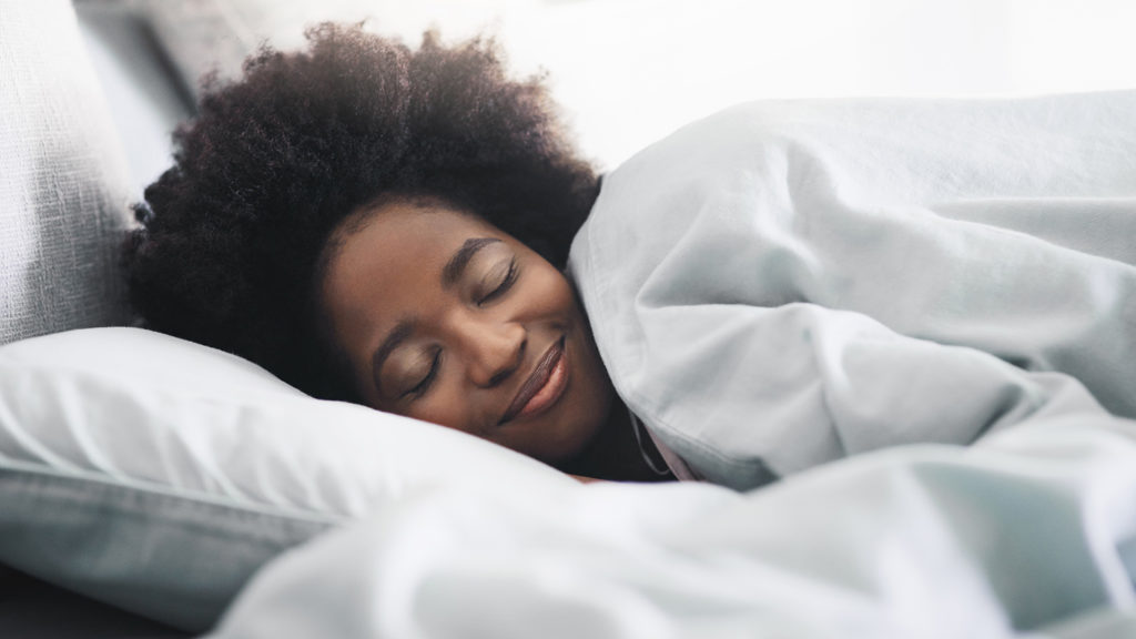 Royalty-Free Stock Photo: Young woman in bed acknowledging the importance of sleep.