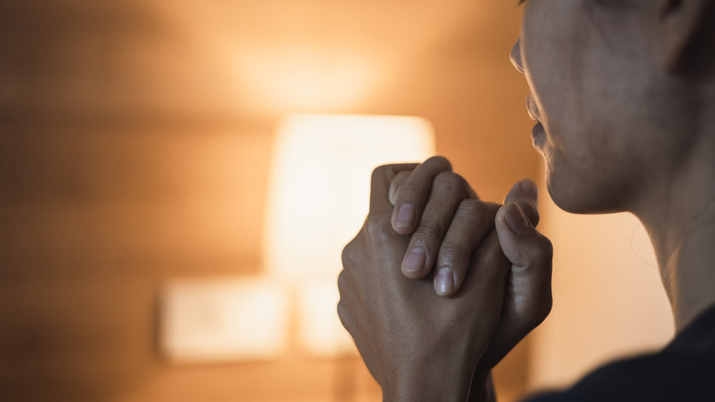 Royalty-Free Stock Photo: Woman praying before bed and acknowledging the importance of sleep.