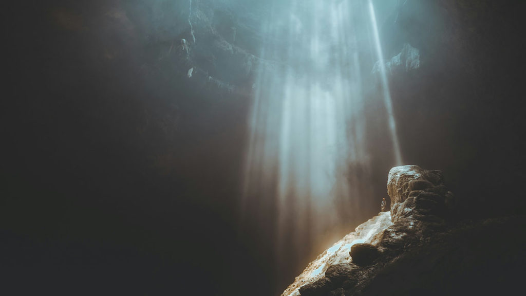 Beams of light shining into a cave remind us our sins are atoned for.