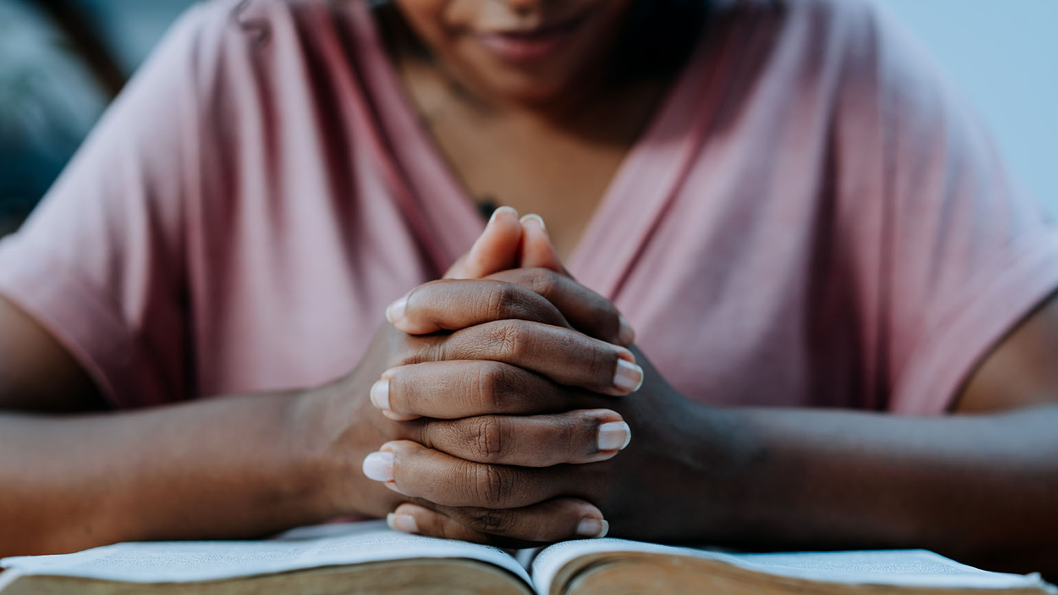 Woman praying a prayer for today with the Bible on the table